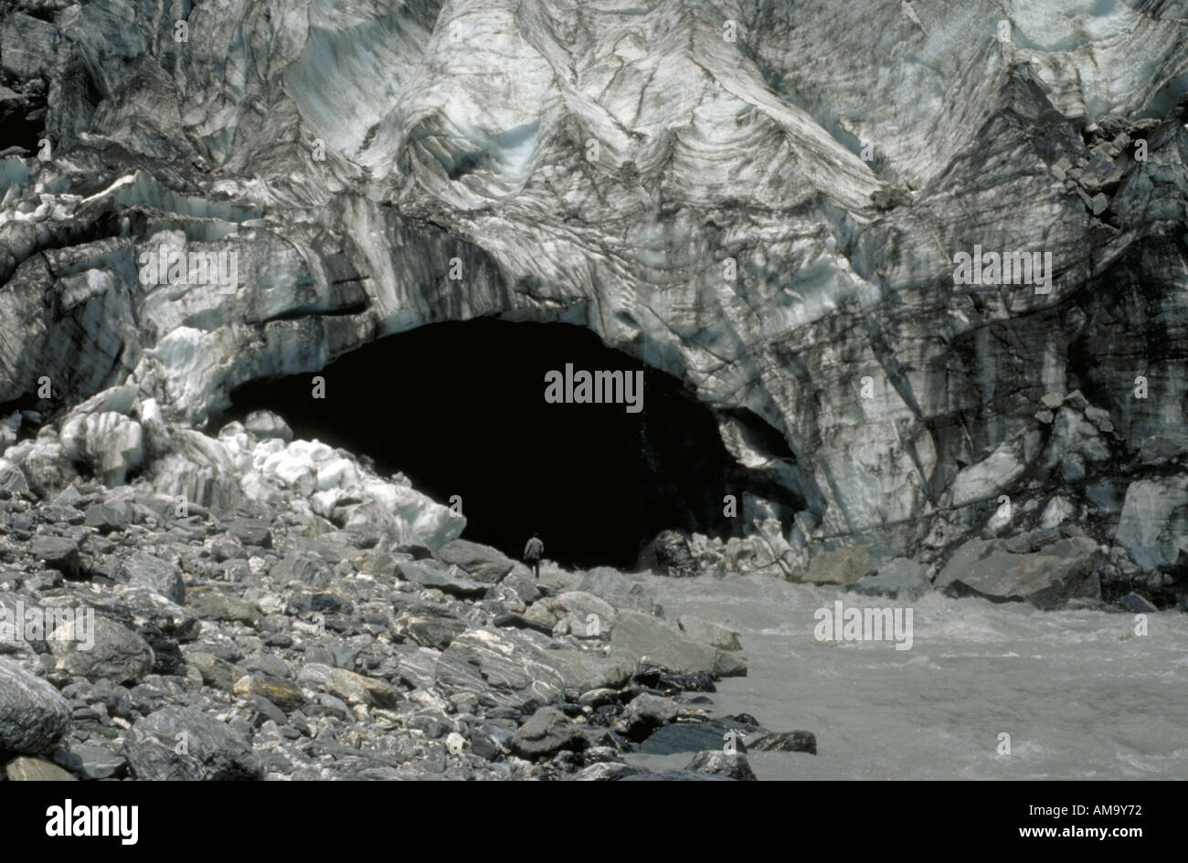 Un homme se tient près de la rivière qui sortent de la bouche de Franz Joseph glacier sur e île du sud de la Nouvelle-Zélande Banque D'Images