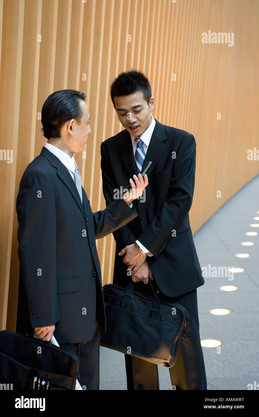 Deux hommes d'affaires à la recherche à un téléphone mobile Banque D'Images