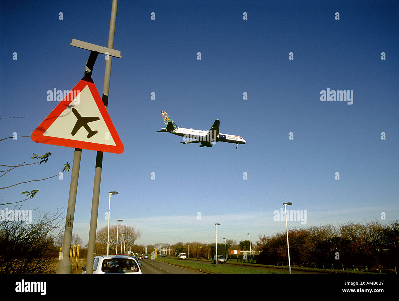 Avion volant bas road sign avec un avion à l'atterrissage à l'aéroport de Heathrow en arrière-plan Banque D'Images