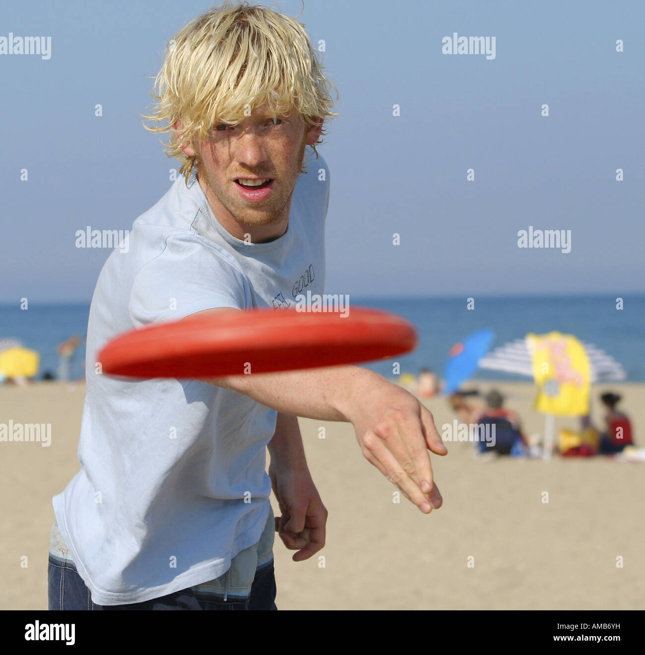 Jeune homme blond à la plage de lancer un frisbee à l'appareil photo Photo  Stock - Alamy