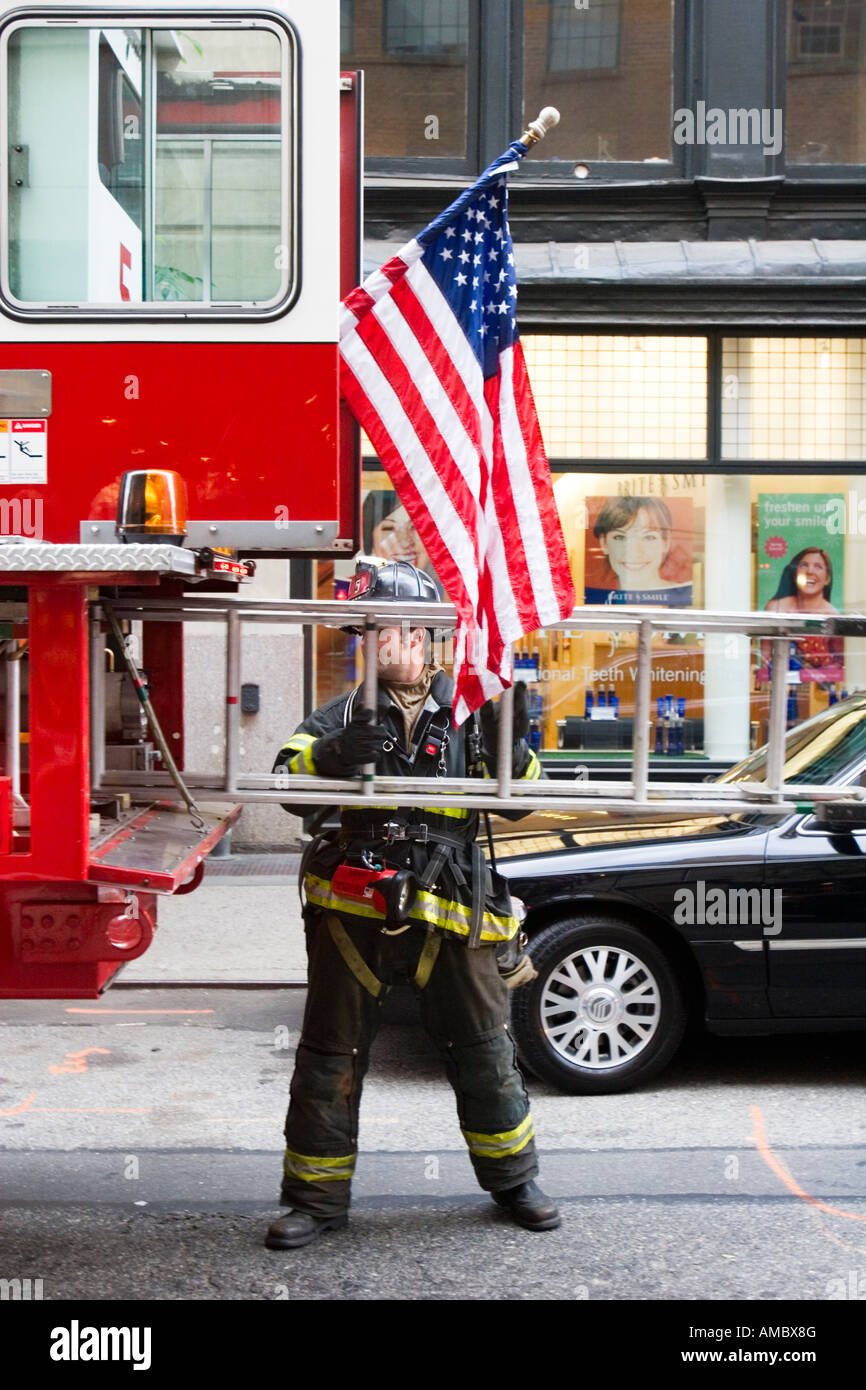 Un pompier de la ville de New York tirant une échelle sur le camion d'incendie Banque D'Images