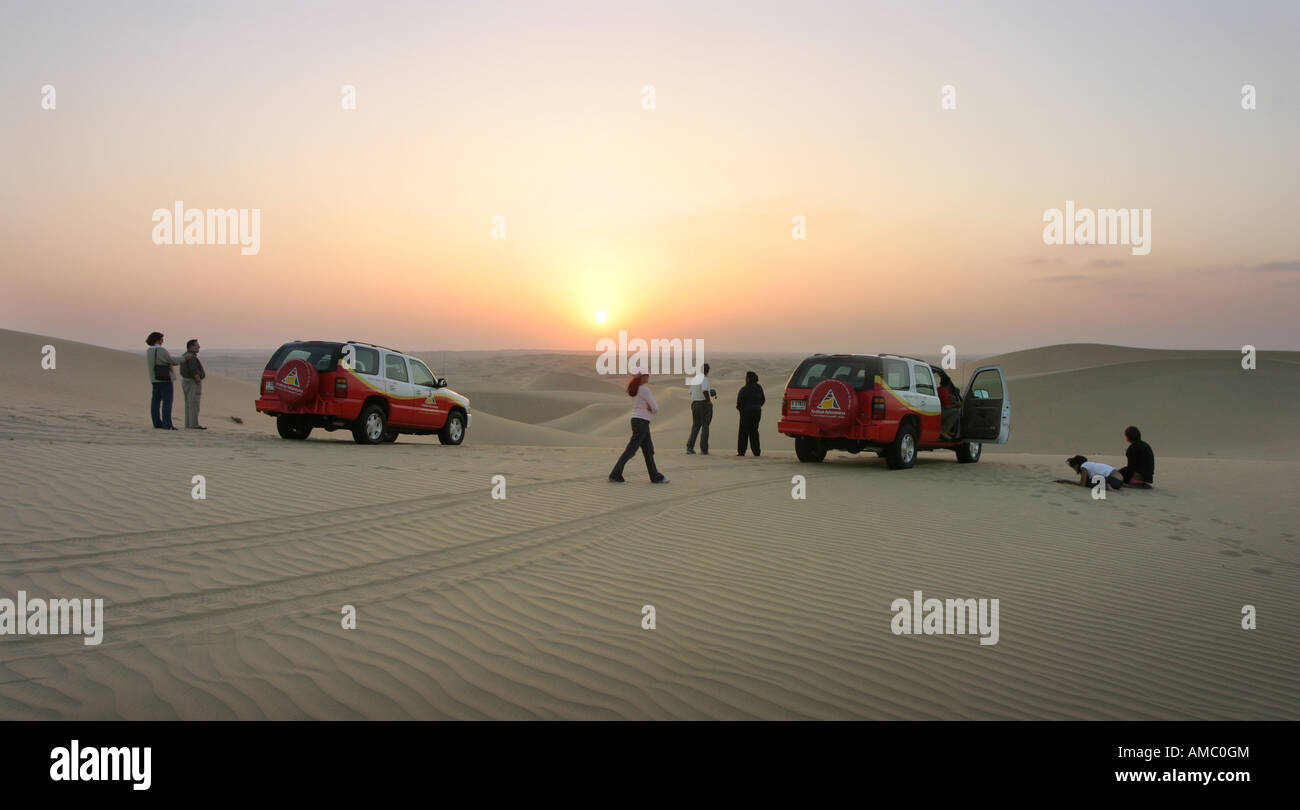 Les touristes sur un circuit en voiture à quatre roues pour voir le coucher du soleil dans le désert d'arabie, Abu Dhabi, UAE Banque D'Images