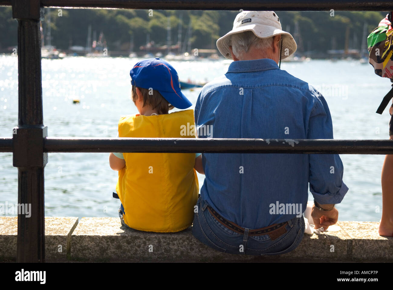 Une vue arrière de deux personnes assises sur le mur donnant sur la rivière fowey cornwall dans Banque D'Images