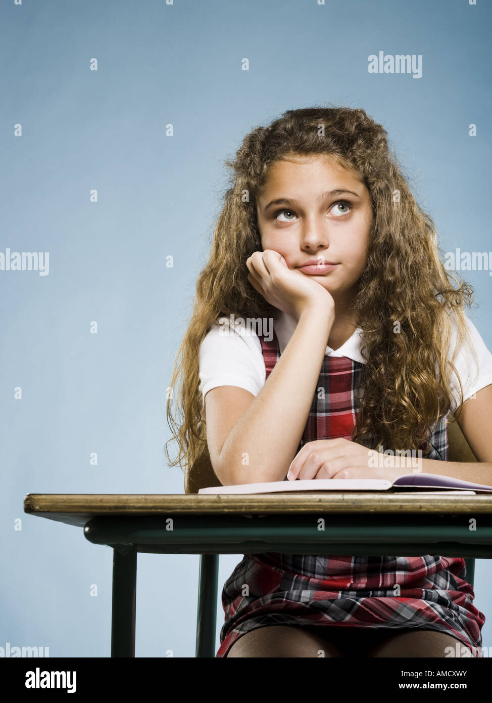 Girl sitting at desk with workbook à ennuyer Banque D'Images