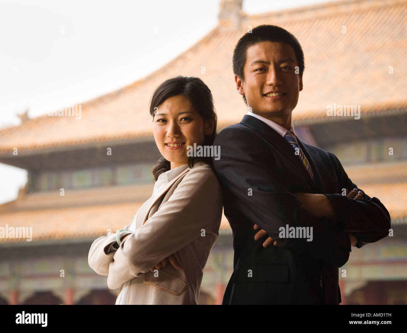 Businessman and woman standing with arms crossed et dos avec pagoda en arrière-plan Banque D'Images
