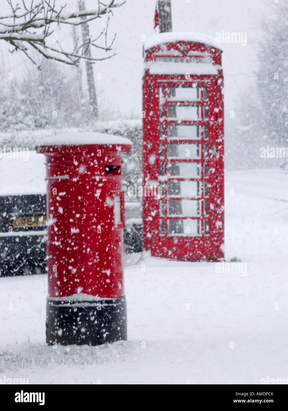 Village rural scène de rue hiver & flocons tomber autour de British Telecom téléphone rouge fort et royal mail pilier lettre fort Essex England UK Banque D'Images