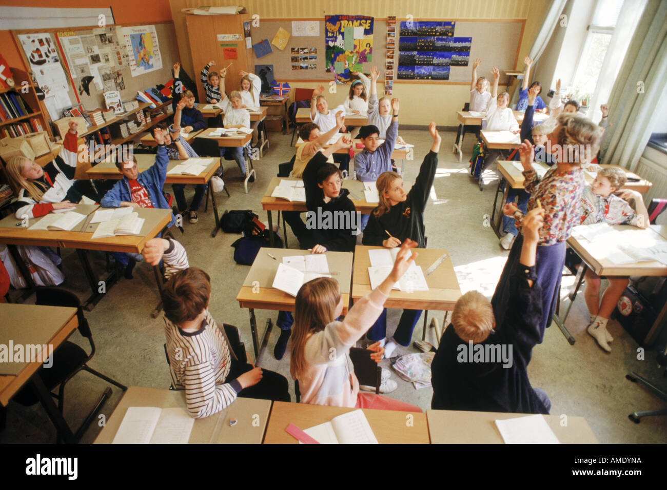 Les enfants de l'école élémentaire assis à un bureau individuel dans la classe suédois les mains pour répondre aux questions de l'enseignant Banque D'Images