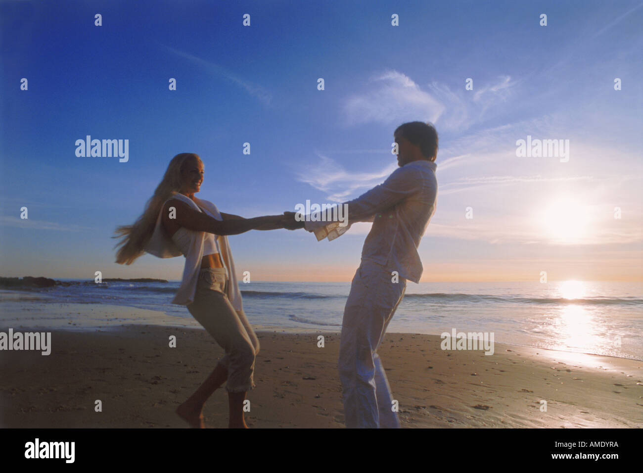 Couple jouant sur la côte de sable au coucher du soleil à Laguna Beach en Californie USA Banque D'Images