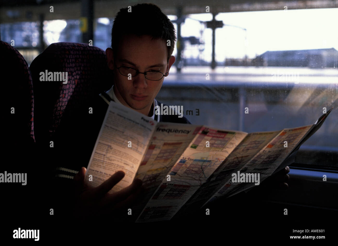Jeune homme en regardant une carte dans un train Banque D'Images