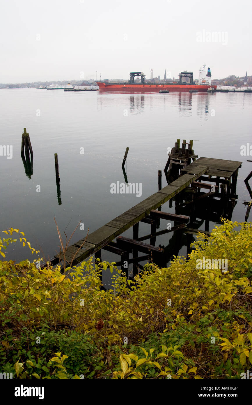 Un semblant d'embarcadère de la rivière Thames, avec un navire de décharger des cargaisons de l'autre côté de la rivière Banque D'Images