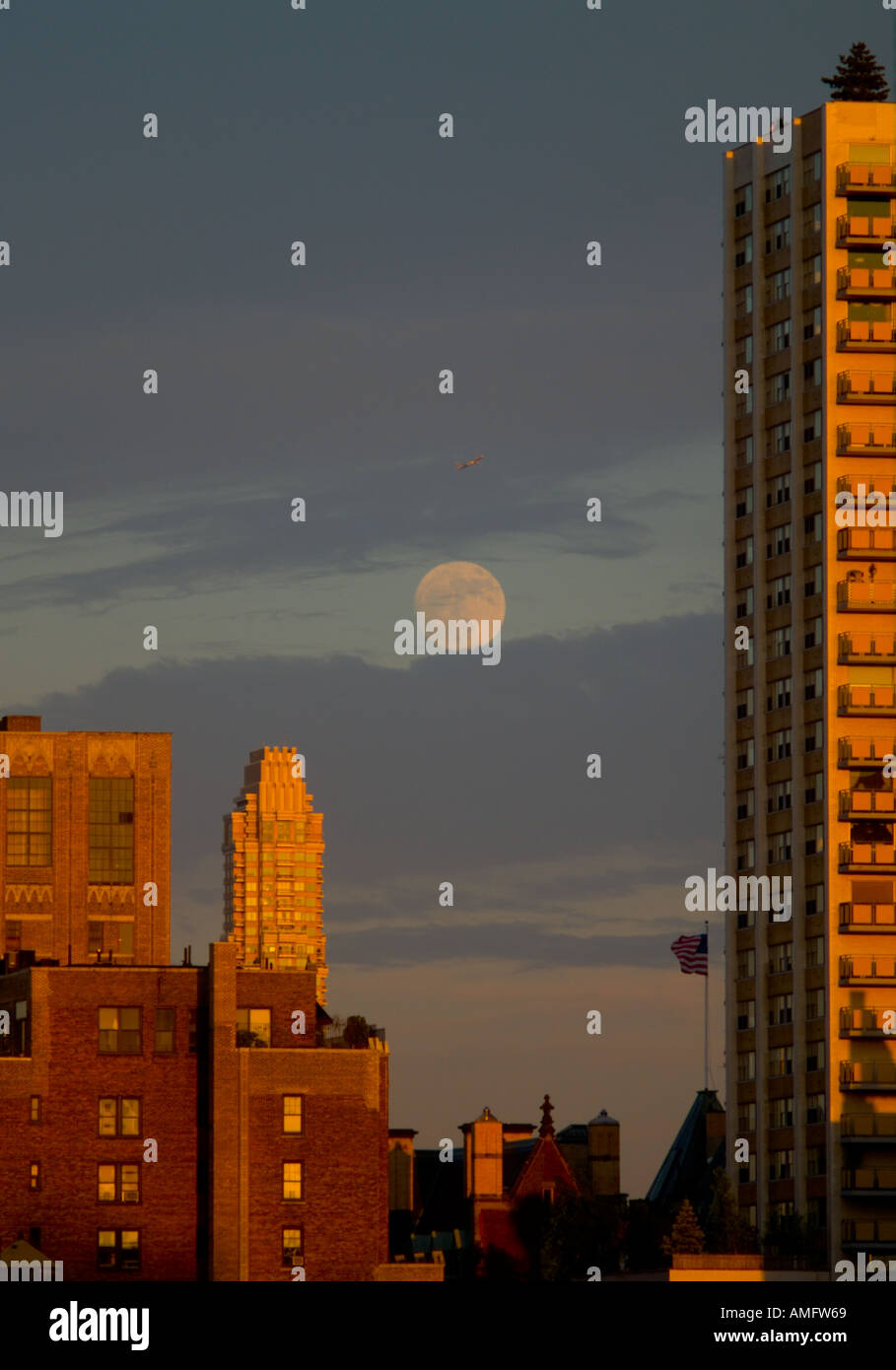 Un avion survole la lune alors que le soleil de fin de soirée s'allume les bâtiments de New York Banque D'Images