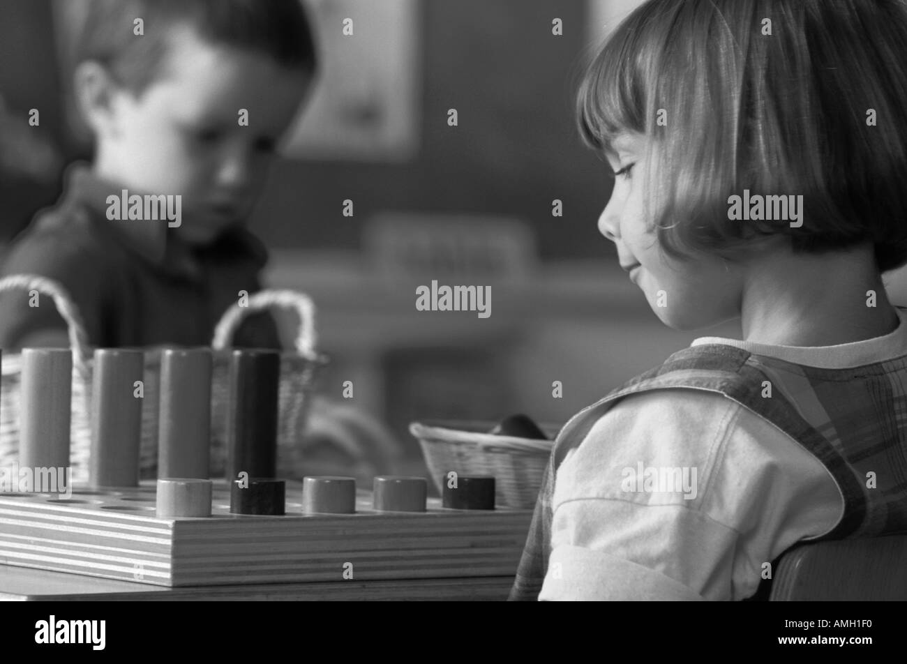 Photo en noir et blanc d'une femme de race blanche à jouer avec des élèves d'âge préscolaire l'enseignement en classe de jouets Banque D'Images Photo en noir et blanc d'une femme de race blanche à jouer avec des élèves d'âge préscolaire l'enseignement en classe de jouets Banque D'Images