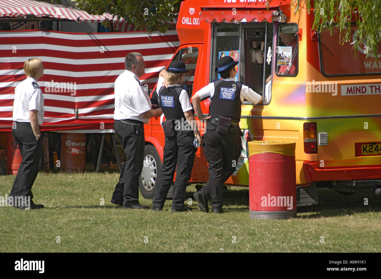 Les agents de soutien communautaire de la police prendre une pause boisson ou une glace à l'événement de la communauté locale Banque D'Images