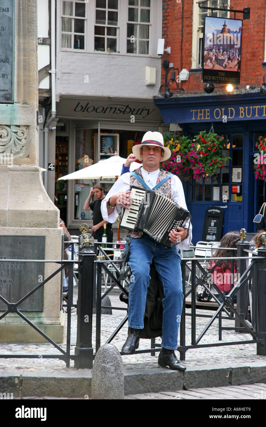 Âge moyen des hommes perchés busker assise sur une balustrade de fer portant un chapeau de paille à l'accordéon musique dans la rue Banque D'Images