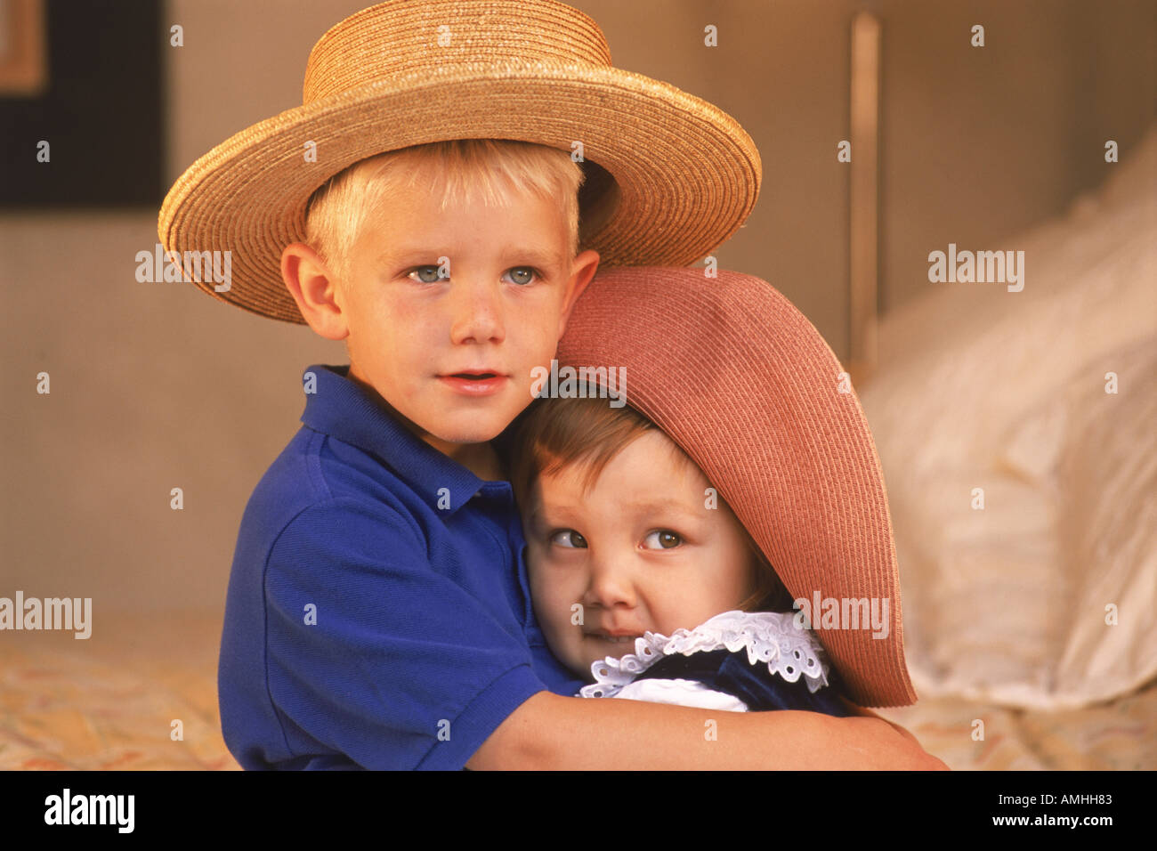 Garçon et fille de 3 à 5 ans serrant avec des chapeaux à la maison Banque D'Images