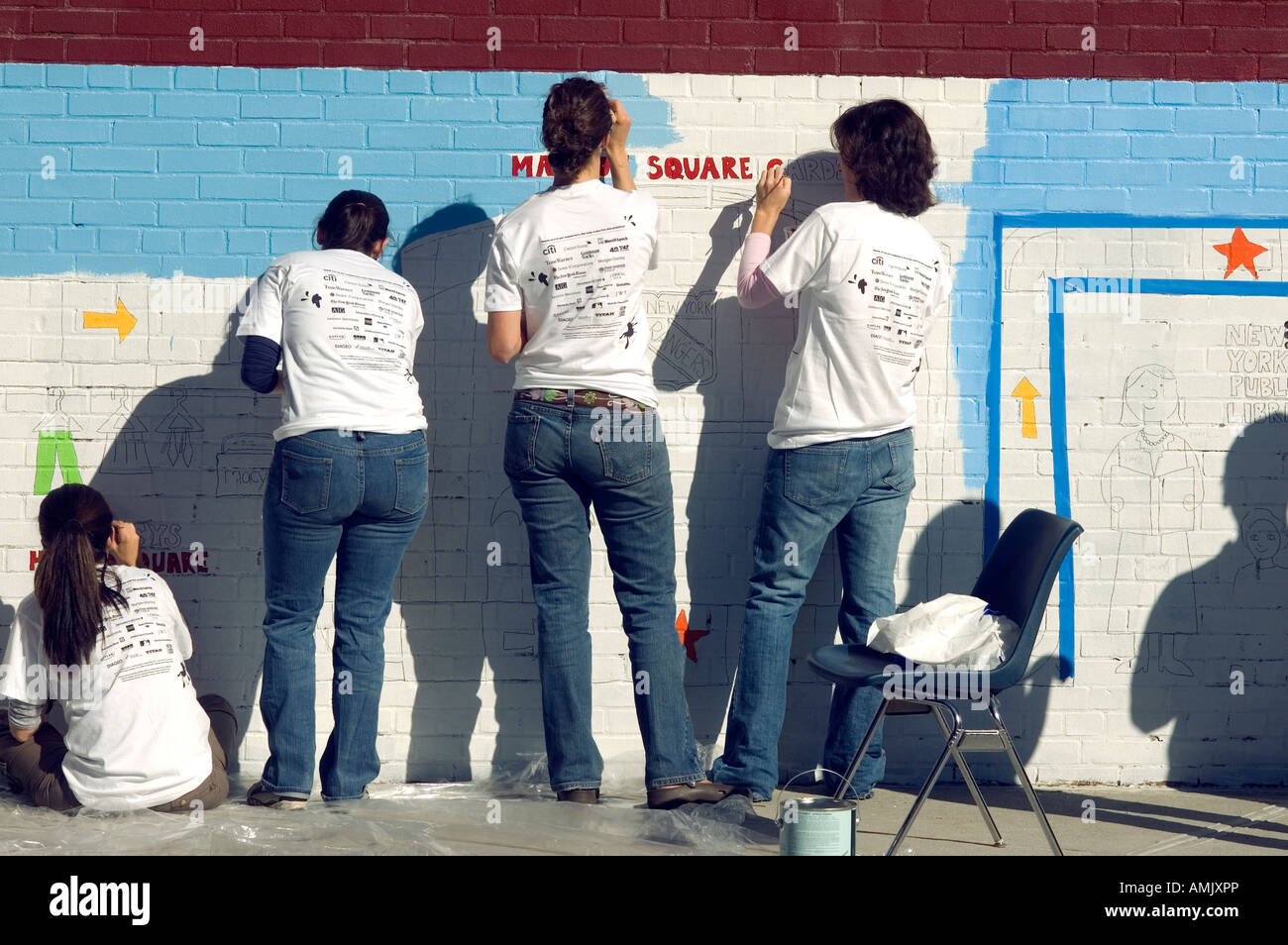 Les bénévoles avec New York Cares une peinture murale sur le côté de l'école PS 33 de Chelsea à New York City Banque D'Images