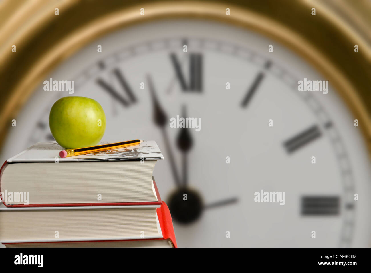 Livres d'étudiants avec une pomme verte et un crayon pointu en face d'une horloge murale Banque D'Images