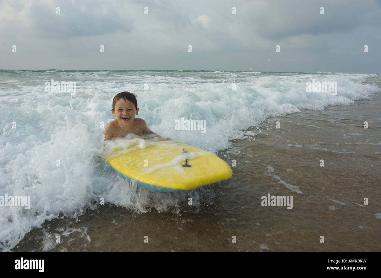 Six ans les vagues de surf avec un body-board. Banque D'Images