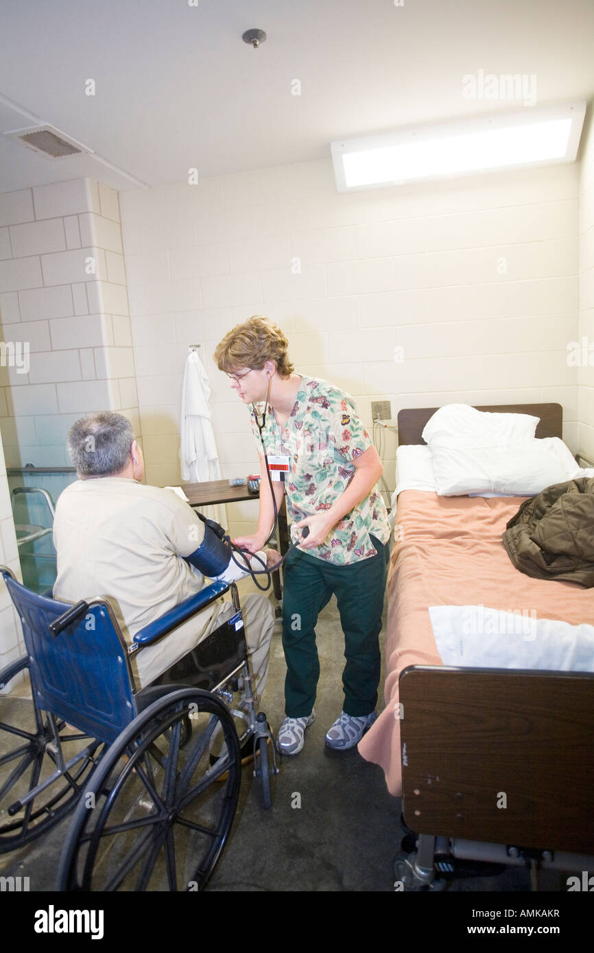 Contrôle de la pression artérielle de l'infirmière à un fauteuil roulant personnes âgées détenu en prison. Prison à sécurité maximale. Banque D'Images