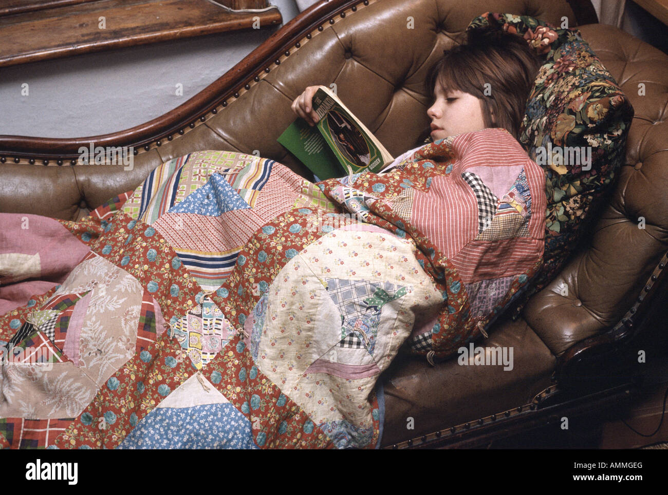 Young Woman Reading sur une chaise longue recouvert d'une courtepointe Banque D'Images