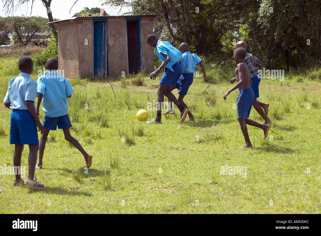 Les enfants en uniformes bleus à jouer au soccer à l'école près de Parc national de Tsavo Kenya Afrique Banque D'Images