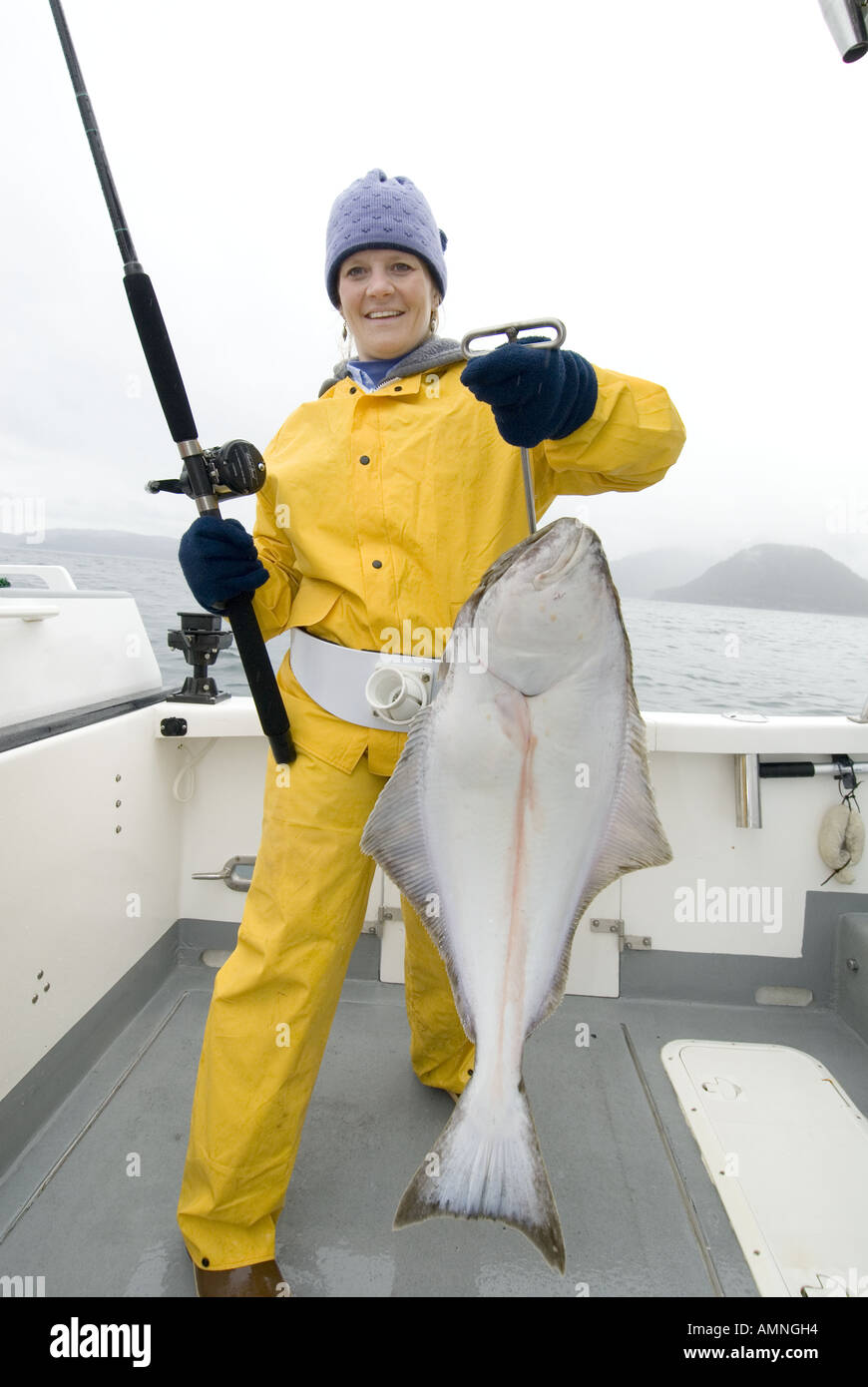 La pêche de l'ALASKA HAPPY WOMAN HOLDING UP HALIBUT COOK INLET PRÈS DE HOMER Banque D'Images