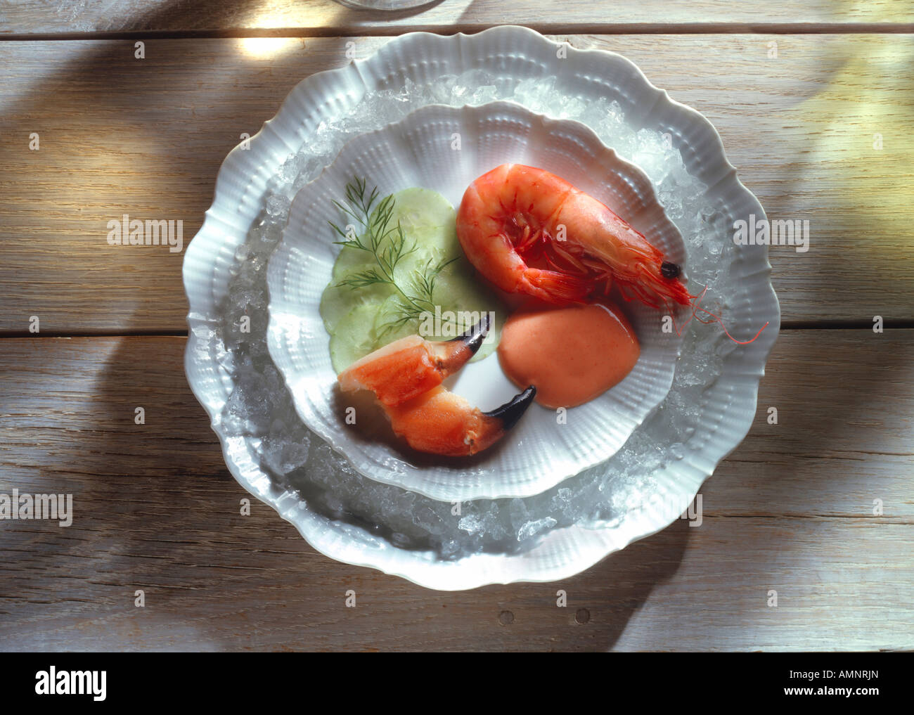 Crevettes dans leur coquille avec des pinces de crabe et de concombre sauce cocktail sur blanc pâle sur bois Banque D'Images