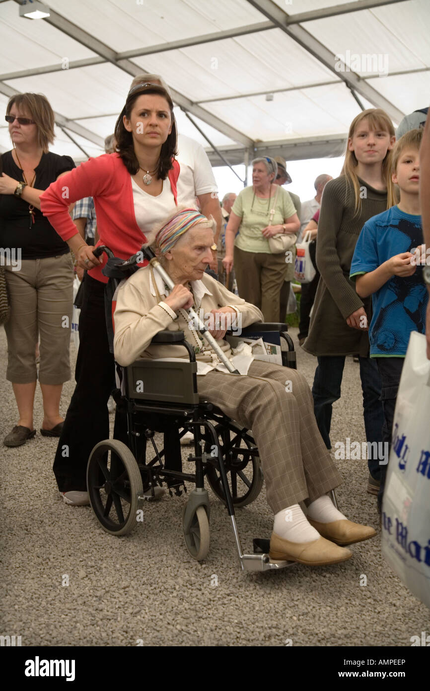 Vieille Femme dans un fauteuil roulant poussé par un parent ou un ami à l'Hampton Court Flower Show UK Banque D'Images