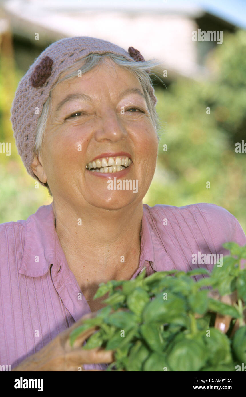 Smiling senior woman holding plants de basilic, close-up Banque D'Images