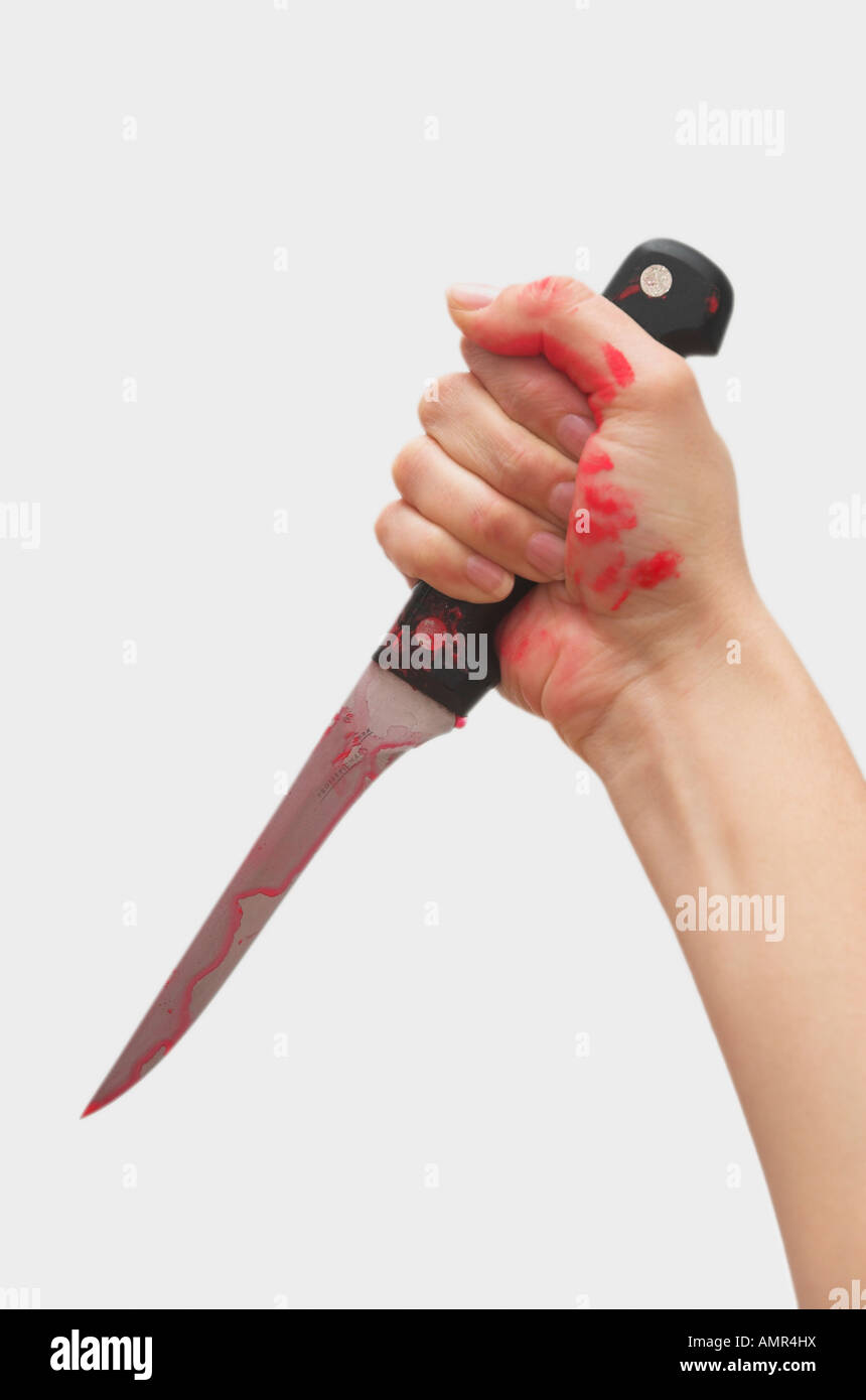 Bras Womans avec de la peinture rouge sur les mains tenant le couteau Banque D'Images