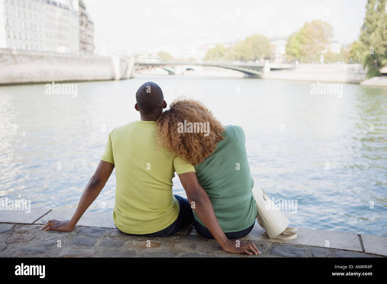 African couple assis à côté de l'eau Banque D'Images