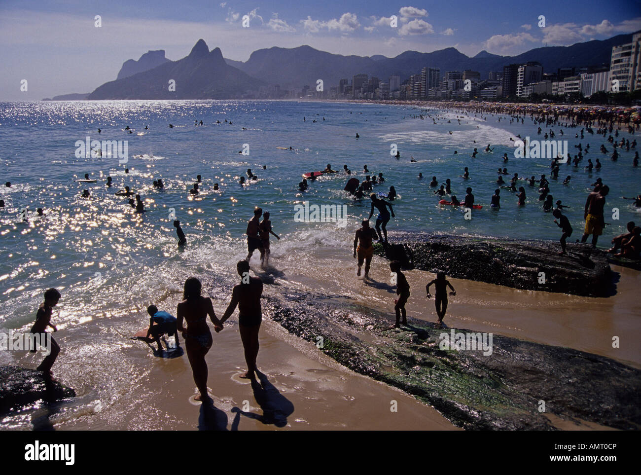 Donner quelques mains jouissent d'Arpoador beach dans une chaude journée ensoleillée et Rio de Janeiro au Brésil. La plage d'Ipanema en arrière-plan. Banque D'Images