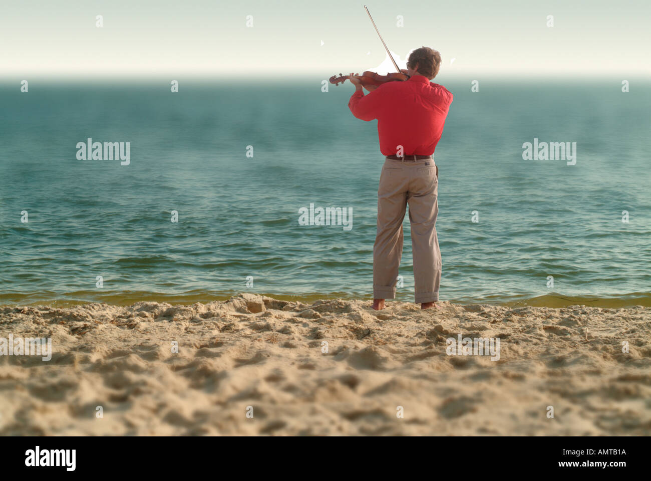 Un homme joue un violon sur la plage Banque D'Images