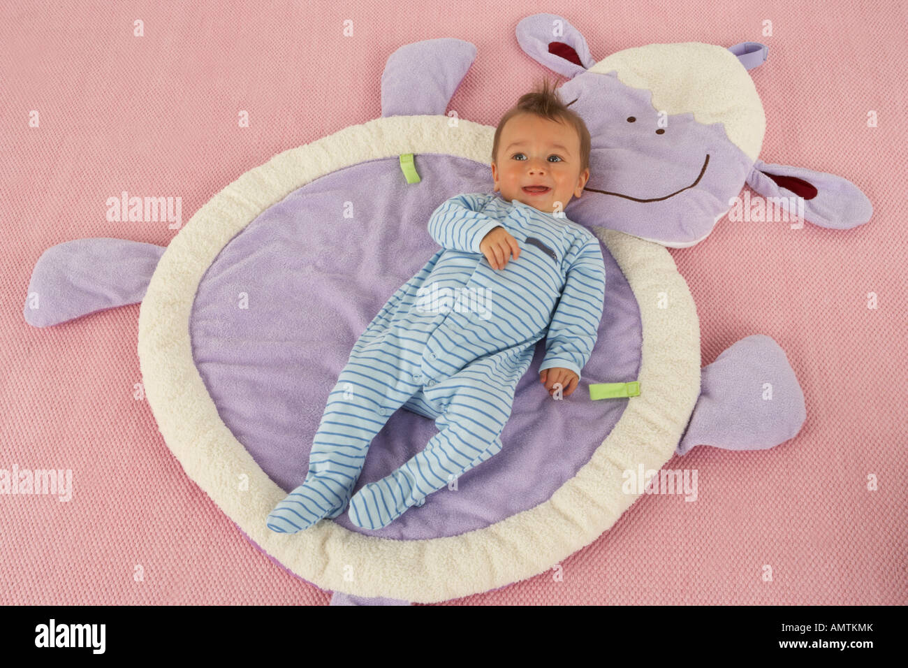 Un bébé est sur le dos sur un tapis d'agneau et de sourires Banque D'Images