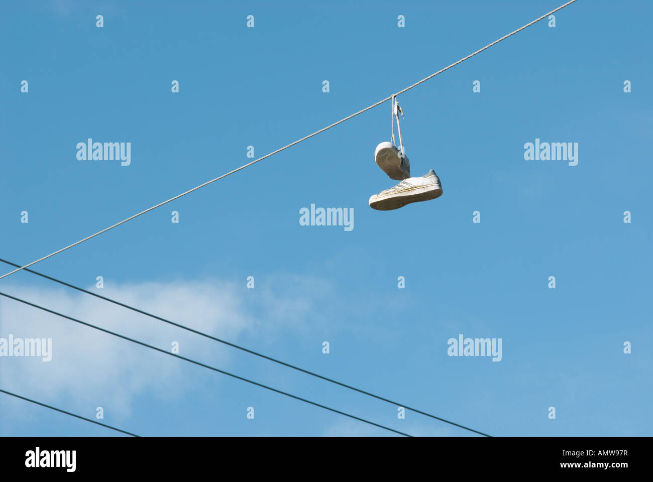 Une paire de baskets blanches suspendues à des lignes électriques après avoir été jetés là comme une blague d'adolescent Banque D'Images