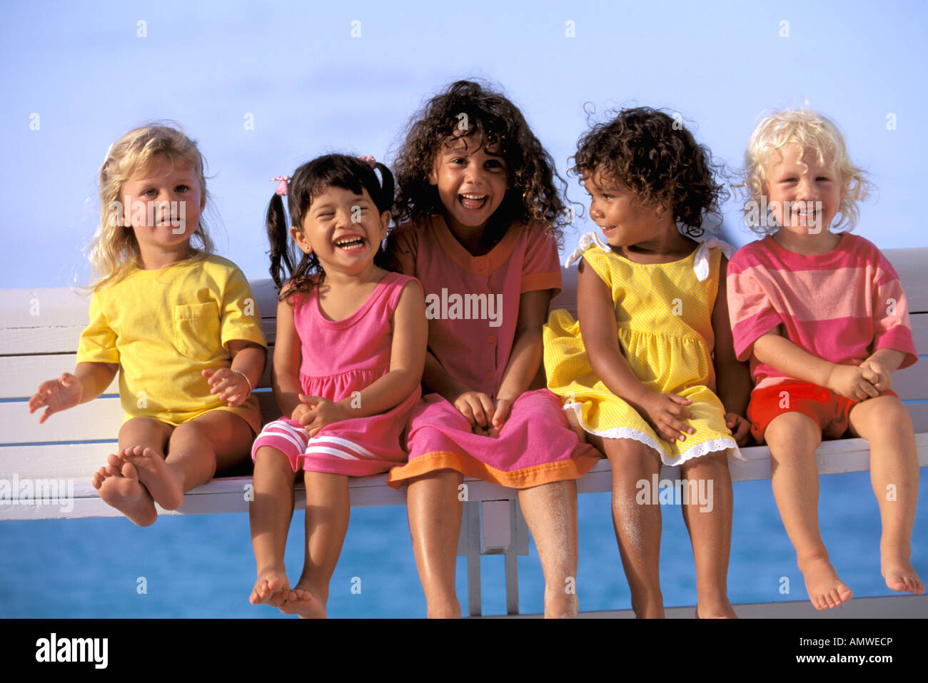 USA, Hawaii. Groupe multiethnique d'enfants assis sur un banc Banque D'Images