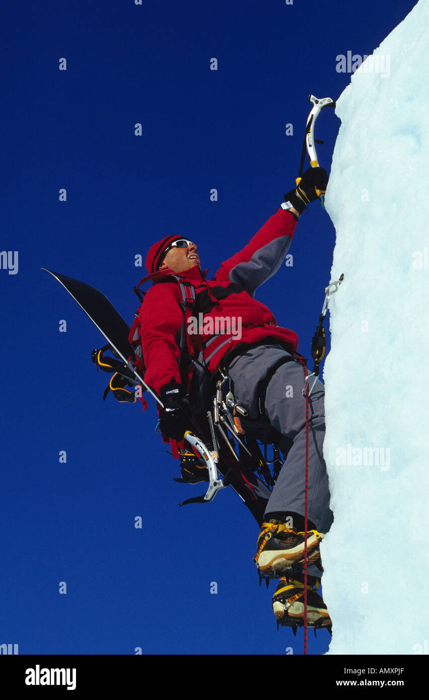 Grimpeur sur glace écailles face avec Snowboard ride pour l'arrière de la maison de montagne. Banque D'Images