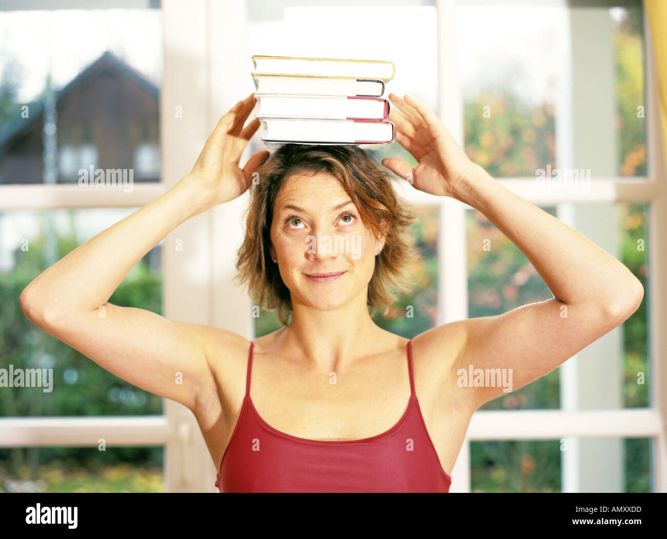 Young woman balancing books on head Banque D'Images