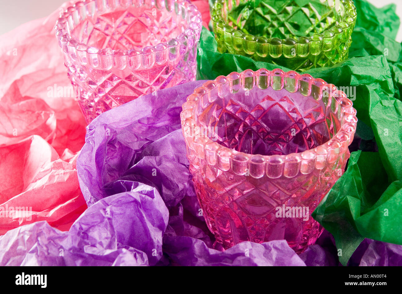 Ensemble de trois multi-verre verres colorés, être enveloppé dans le rose, vert et lilas de papier tissu à un cadeau. Banque D'Images