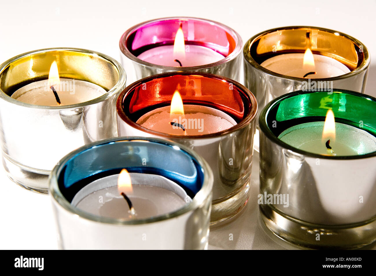 Plateau en verre multicolores s'allume avec des bougies allumées. Il est indiqué sur un fond blanc Banque D'Images