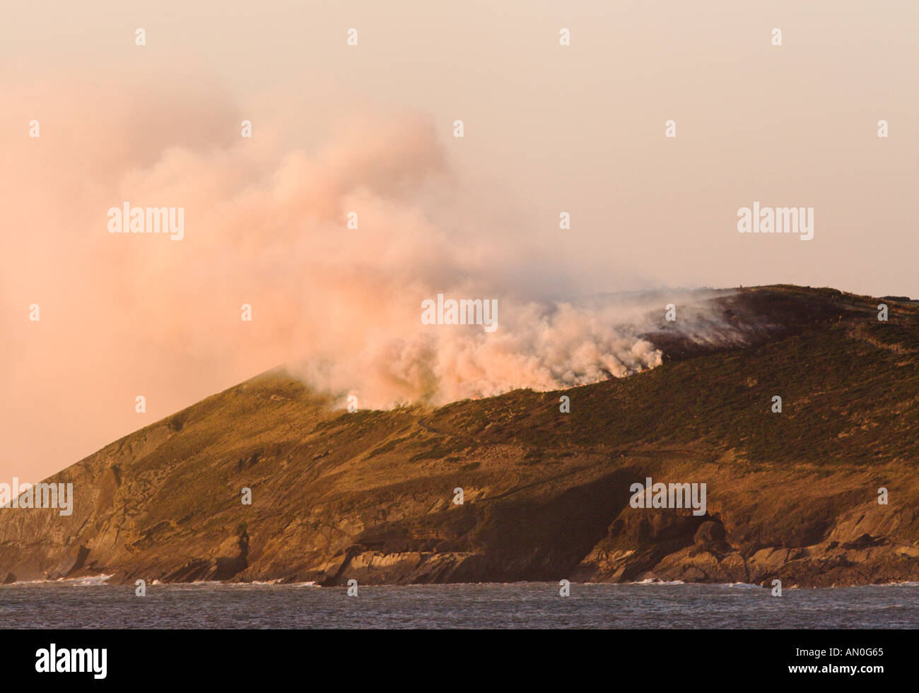 Vue sur la baie de Croyde Point Baggy avec grand feu d'ajoncs sur colline avec des nuages de fumée qui monte le nord du Devon en Angleterre Banque D'Images