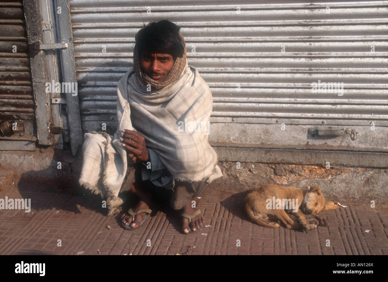 Homme assis à côté de route avec chiot endormi à côté de lui, du Punjab, en Inde. Banque D'Images