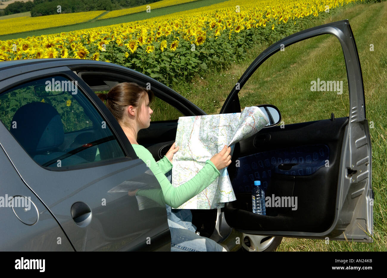 Jeune femme perdue dans la campagne dans sa voiture en regardant une carte Banque D'Images