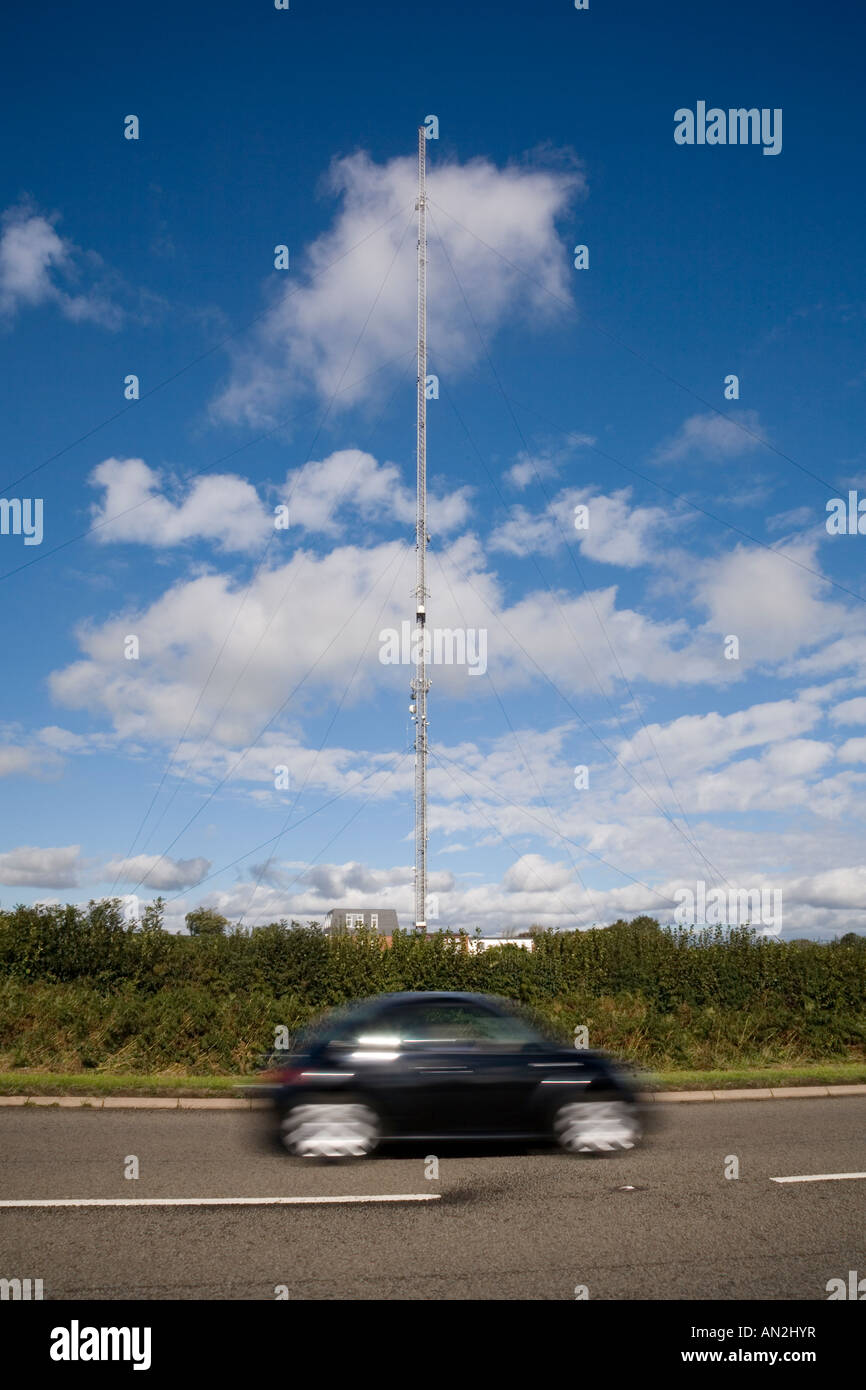 Le mât de l'émetteur à St Hilary dans la vallée de Glamourgan, au pays de Galles, s'est mis contre un ciel bleu avec un peu de nuages et une voiture de passage au premier plan Banque D'Images