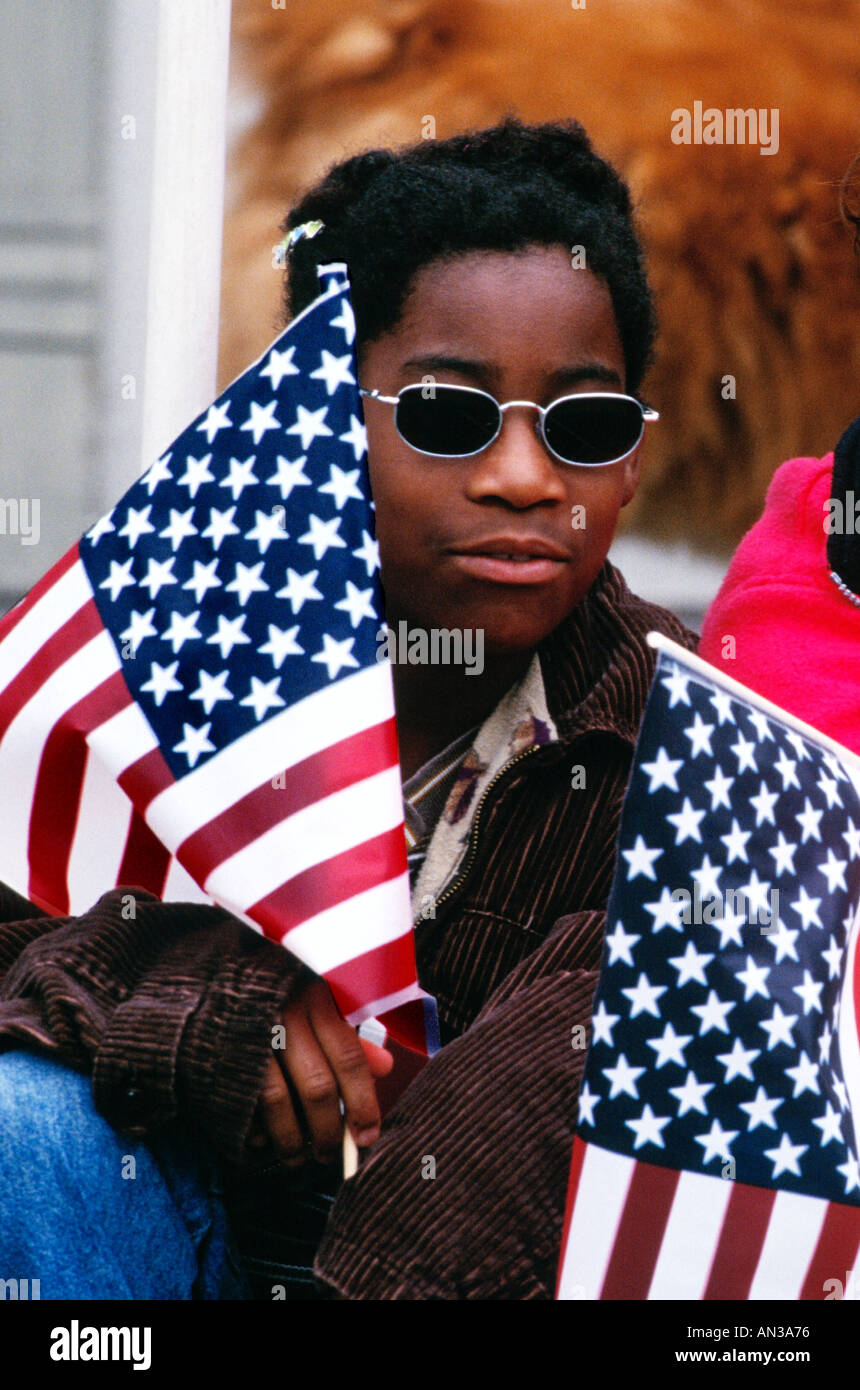 Afrian American female teen avec des drapeaux américains à regarder la parade du 4 juillet Banque D'Images