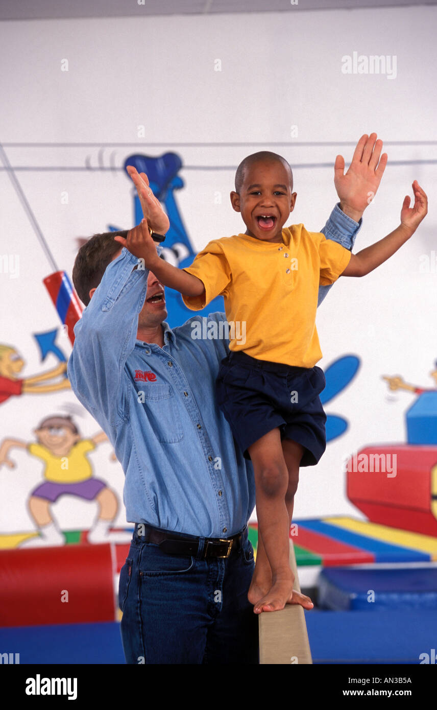 Male trainer coaching African American boy en gymnastique Banque D'Images