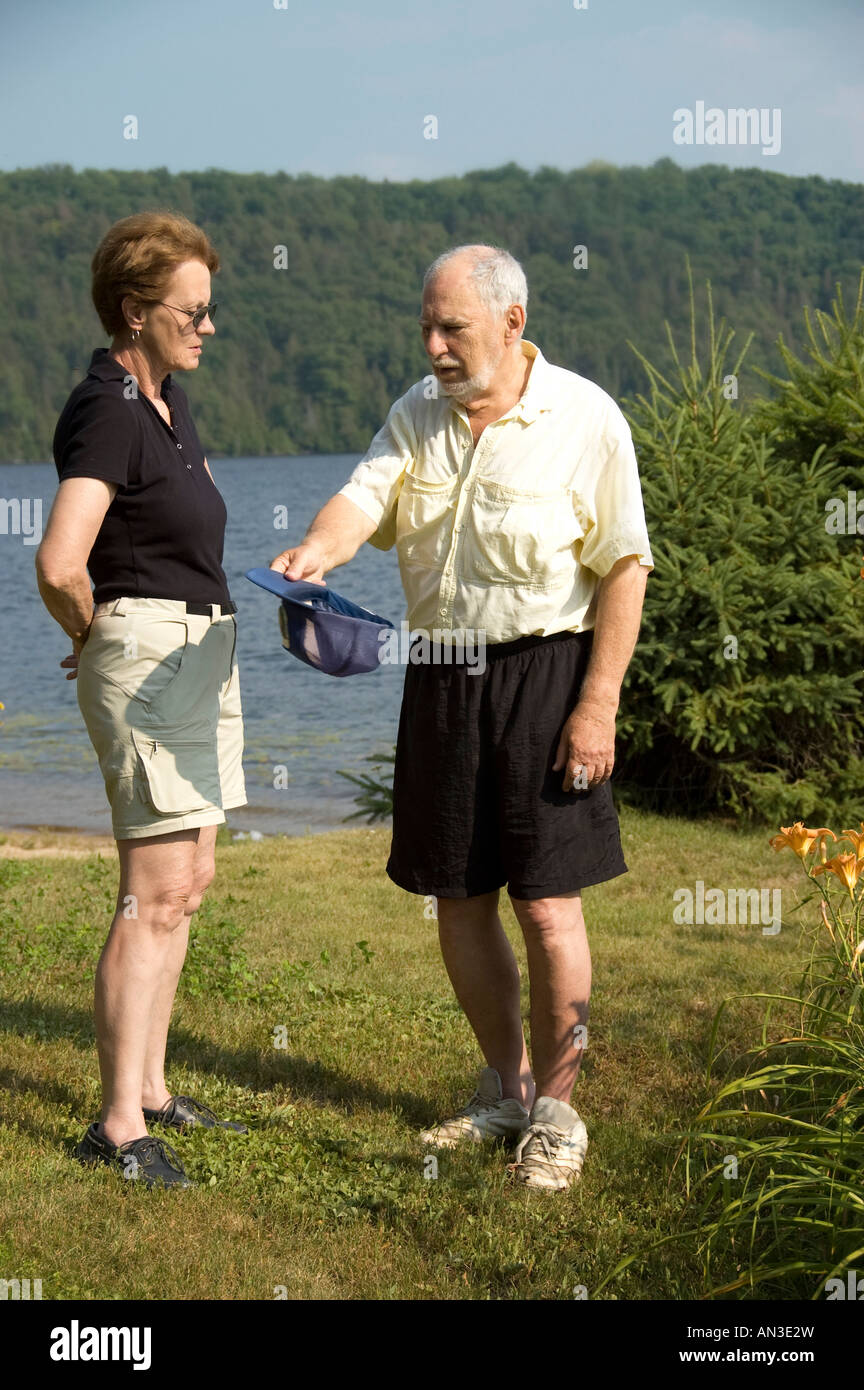 Les personnes âgées l'homme et la femme d'avoir des discussions sur la plage à côté d'un lac bleu Banque D'Images