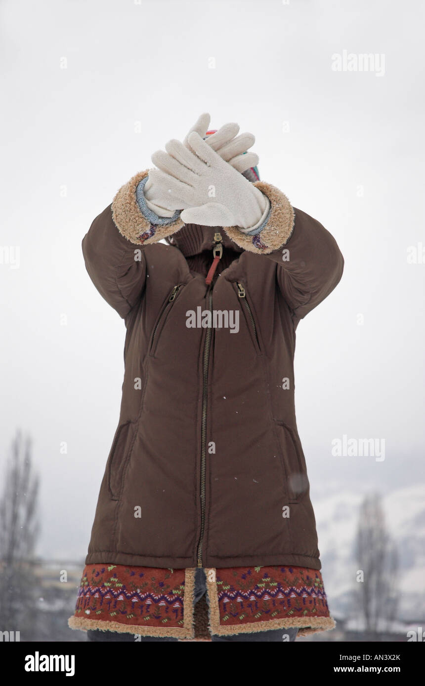 Woman holding up gants en face de visage Banque D'Images