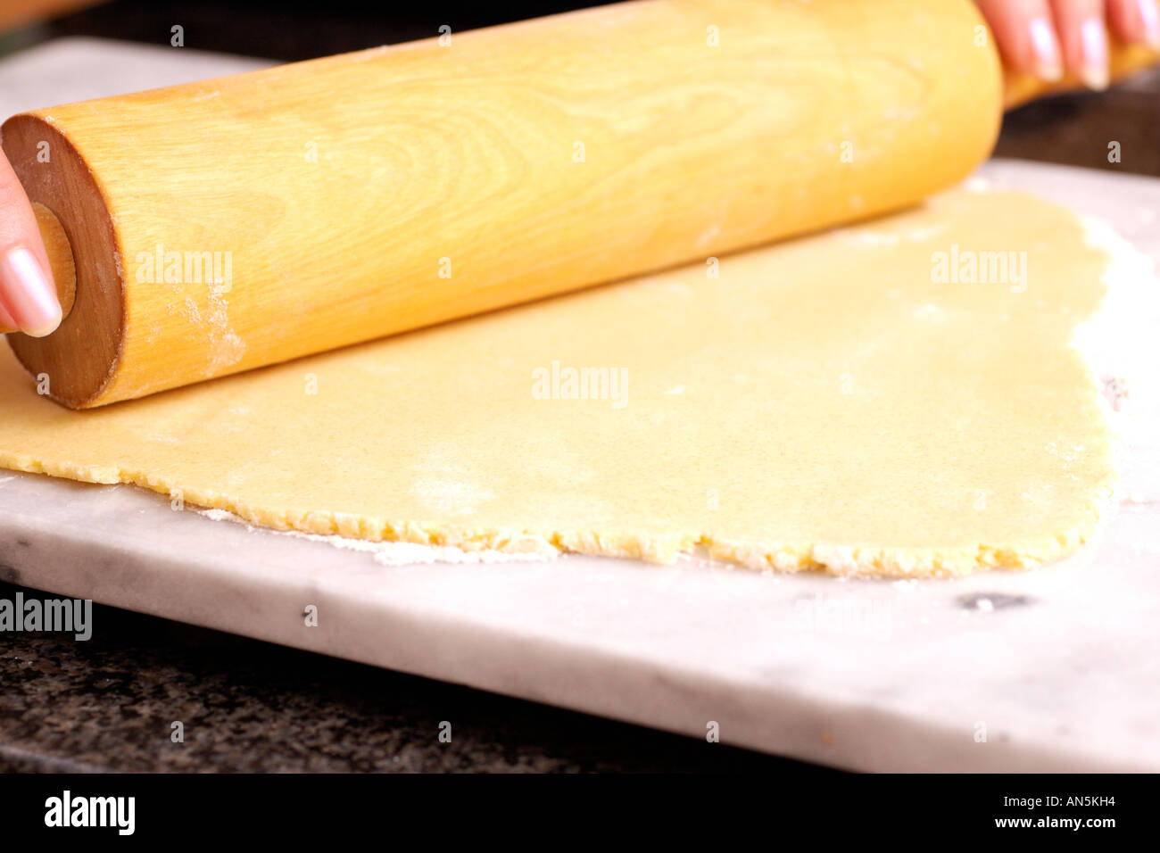 Rouler la pâte sablée en femme avec un rouleau à pâtisserie sur la plaque  de marbre Photo Stock - Alamy