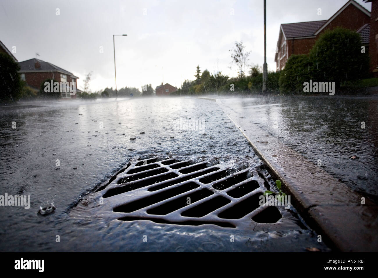 L'eau de pluie qui s'écoule dans un tuyau d'évacuation sur le côté d'une route à Redditch UK Worcestershire pendant un orage d'été Banque D'Images